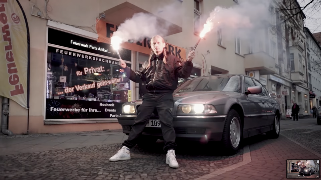 Mann mit Bengalo vor Auto
